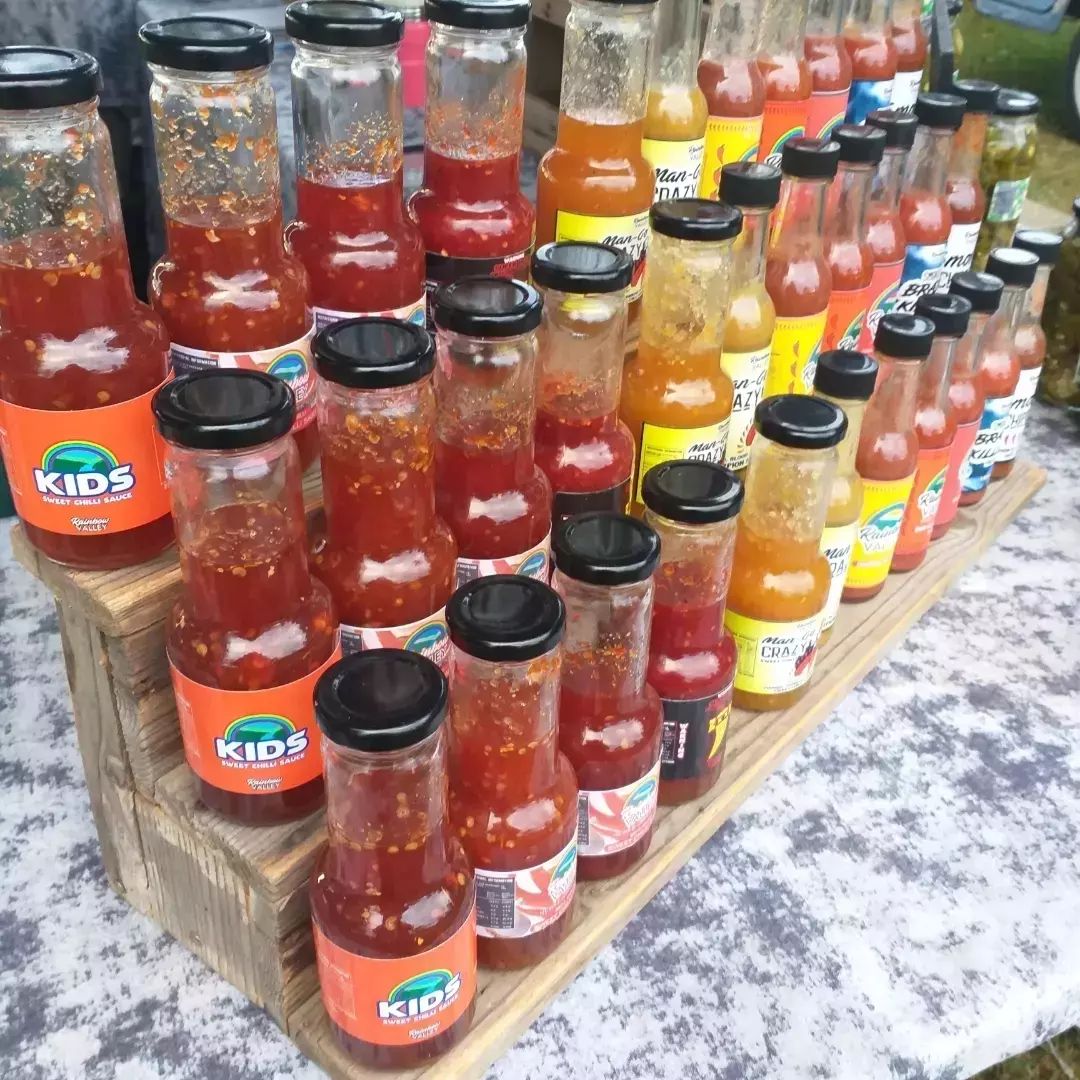 Rows and rows of Rainbow valley  products at a market stall.  Famous for their chili sauces, the kids are not forgotten and there's a sweet sauce or two, so they don't feel left out - Macnuts